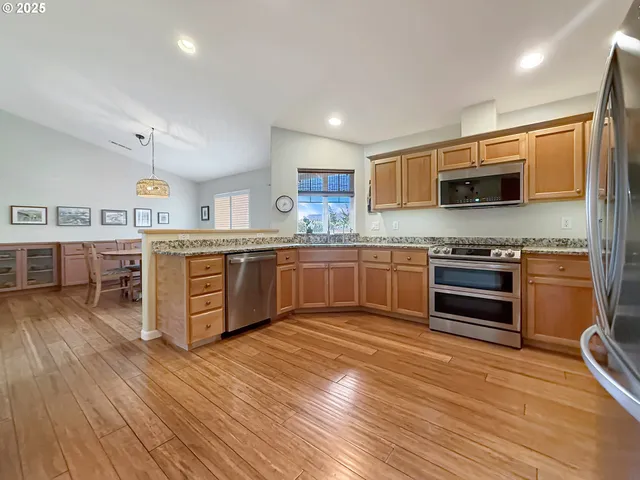 a kitchen with stainless steel appliances wooden cabinets and wooden floor