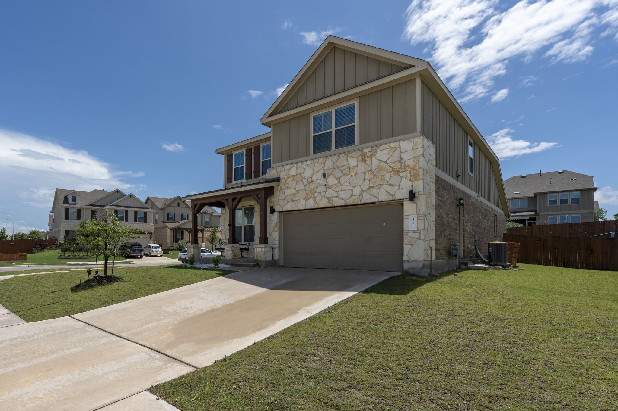 548 Purple Heart Drive Buda, TX 78610 - Photo 34 of 35 A welcoming front exterior features a stone and siding facade with an attached garage and a covered porch.