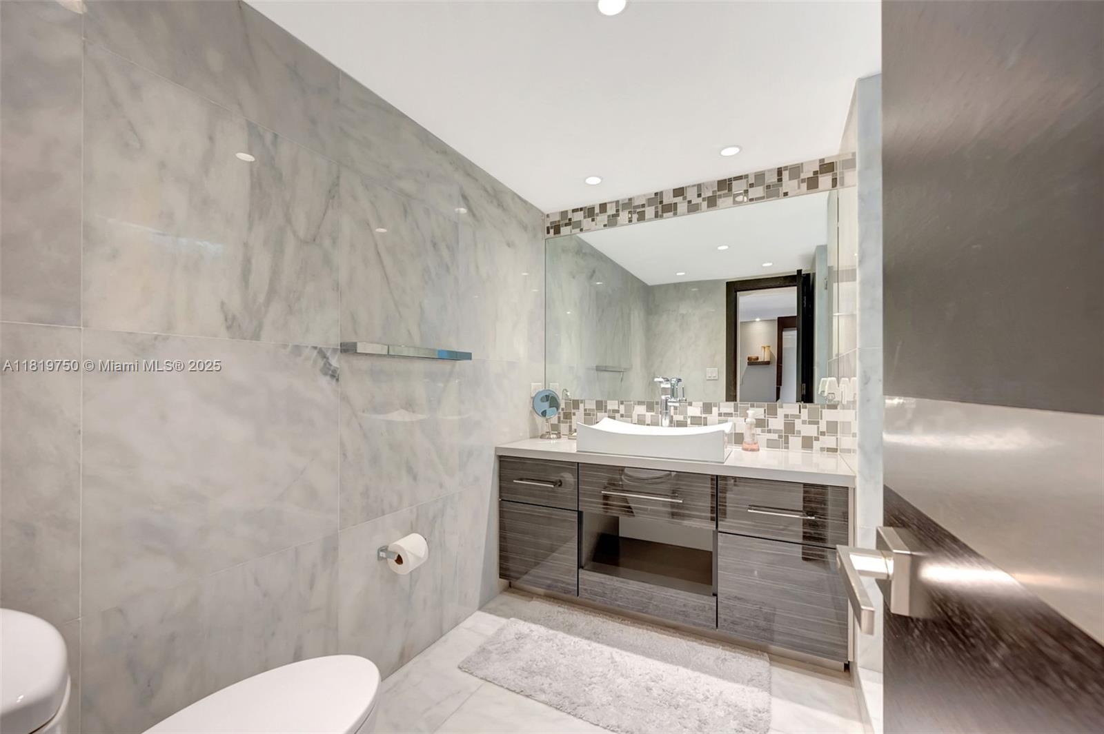 2301 Collins Avenue, Unit 307 Miami Beach, FL 33139 - Photo 6 of 17 a spacious bathroom with a toilet a sink and mirror