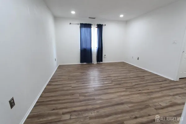 a view of an empty room with wooden floor and entryway