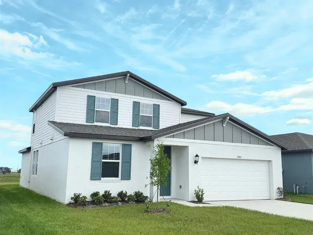 a view of a white house next to a yard and garage