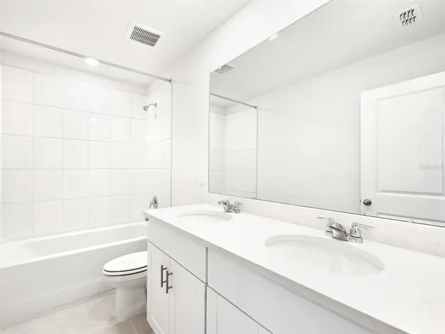 a bathroom with a bathtub shower sink vanity mirror and toilet