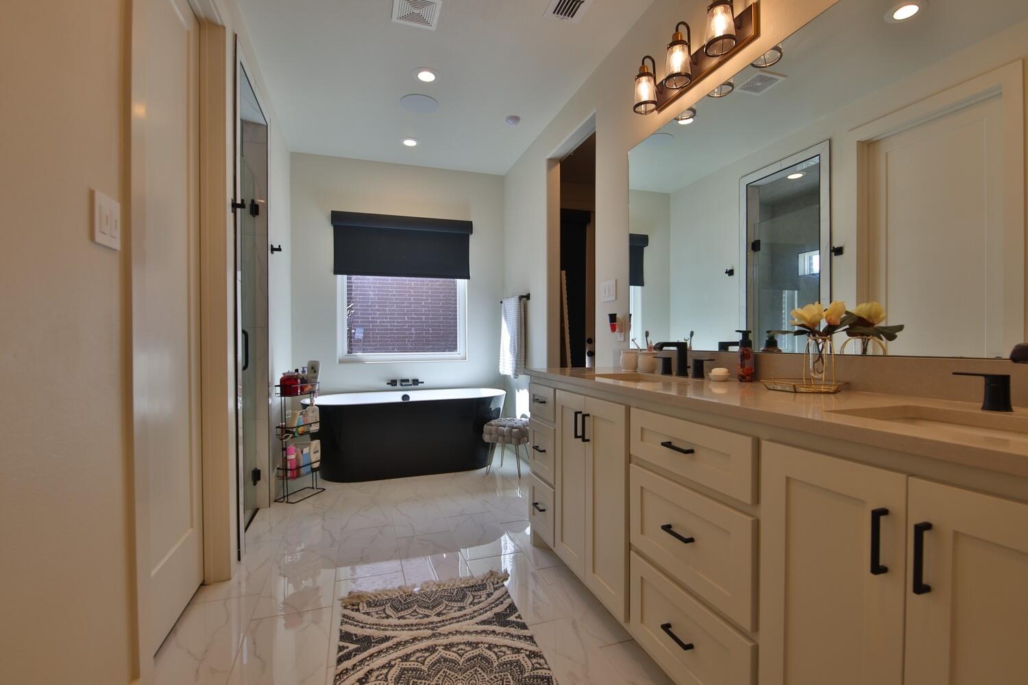 4611 139th Street Lubbock, TX 79424 - Photo 18 of 38 a bathroom with a double vanity sink a mirror and a bathtub