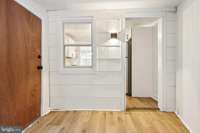 an empty room with wooden floor chandelier fan and windows