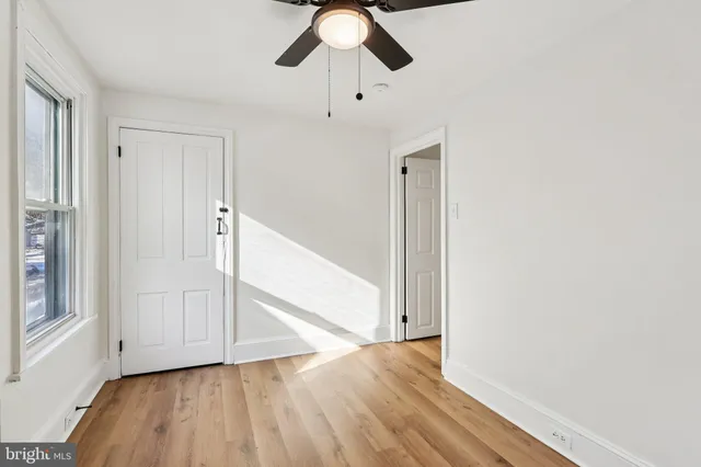 a view of empty room with wooden floor and fan