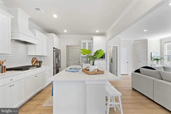 a kitchen with stainless steel appliances kitchen island granite countertop a sink a stove a refrigerator and white cabinets