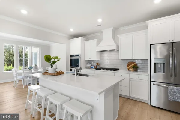 a kitchen with a refrigerator a stove a sink dishwasher and white cabinets with wooden floor