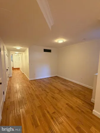 a big room with wooden floor and a kitchen view