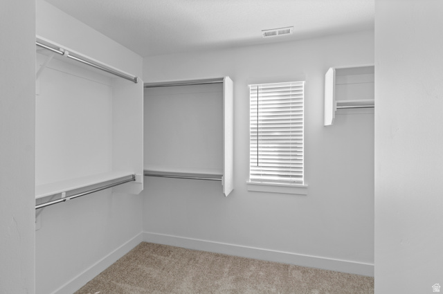 1264 West 500 South, Unit 320 Logan, UT 84321 - Photo 20 of 39 Spacious walk-in closet featuring white built-in shelving, chrome hanging rods, a window with blinds, and light-colored carpet flooring