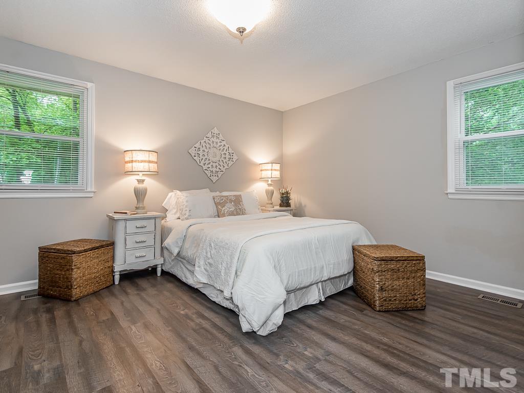 7014 Kemp Road Raleigh, NC 27613 - Photo 19 of 43 a bedroom with a bed and a dresser with wooden floor