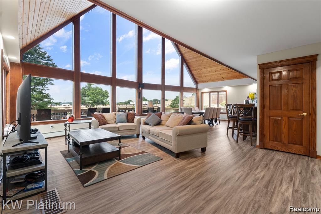1907 Riverside Drive Port Huron, MI 48060 - Photo 5 of 49 Vaulted wooden plank ceilings with exposed beams, expansive window wall, wood-finish flooring, and a built-in wet bar