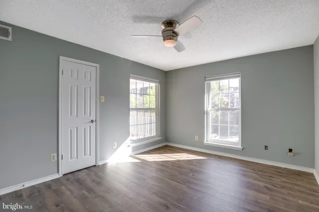 an empty room with wooden floor and windows