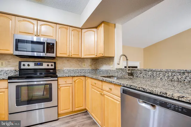 a kitchen with stainless steel appliances granite countertop a stove microwave and cabinets