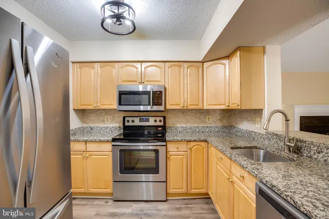 a kitchen with stainless steel appliances granite countertop a sink a stove a microwave and refrigerator