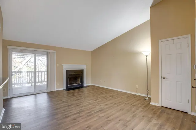 an empty room with wooden floor fireplace and windows