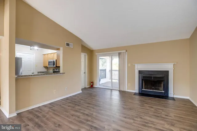 a view of a livingroom with wooden floor and a fireplace