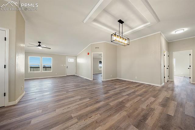 8160 Edison Road Yoder, CO 80864 - Photo 11 of 42 Unfurnished room with dark hardwood / wood-style flooring, crown molding, and ceiling fan with notable chandelier