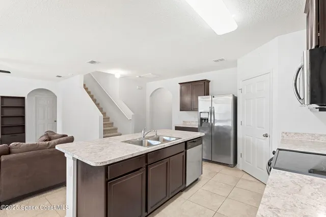 a kitchen with stainless steel appliances kitchen island granite countertop a refrigerator a stove and a sink with granite countertops