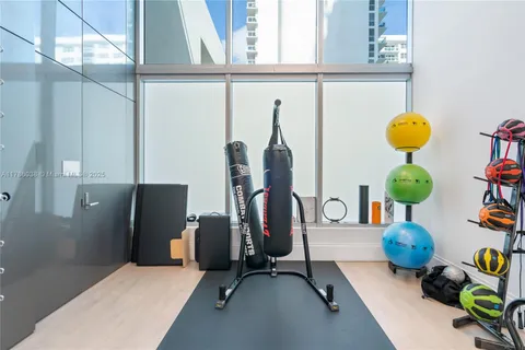 a living room with furniture a large window and gym equipment