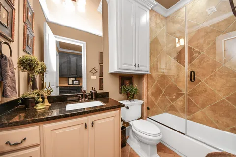 a bathroom with a granite countertop toilet a sink and a mirror