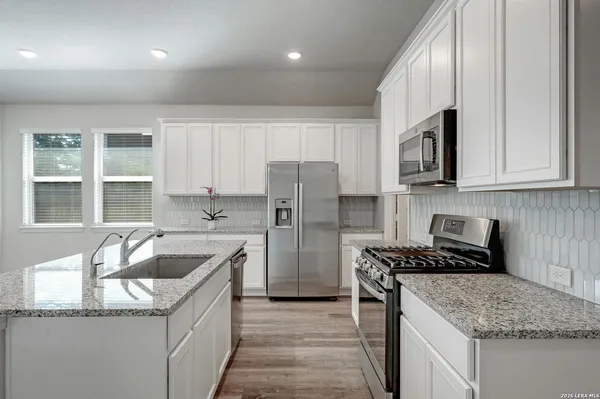 a kitchen that has a sink cabinets counter space and appliances