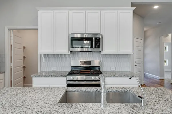 a kitchen with granite countertop a stove a microwave and cabinets