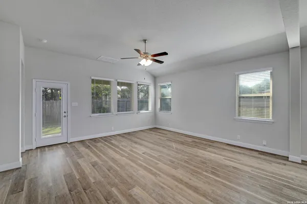 a view of an empty room with a window and wooden floor