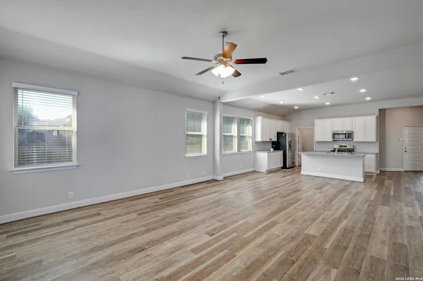 a view of an empty room with window and wooden floor