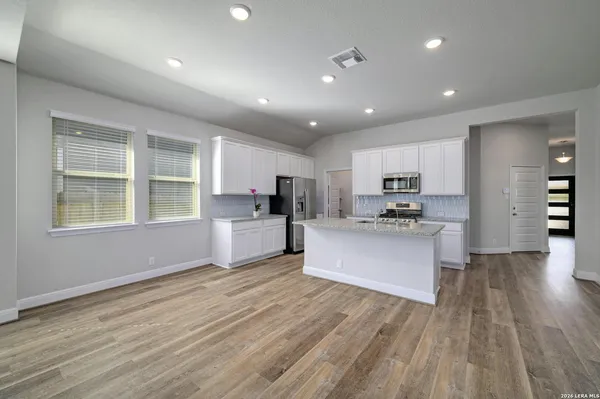 a large kitchen with kitchen island a sink wooden floor and a refrigerator