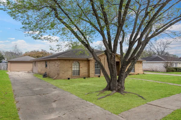a view of a house with a large tree and a yard