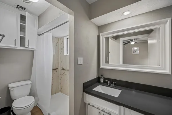 a bathroom with a granite countertop sink toilet and mirror