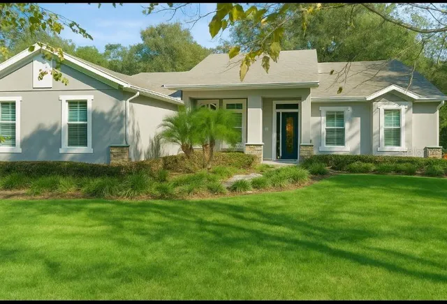 a view of a white house next to a yard with potted plants