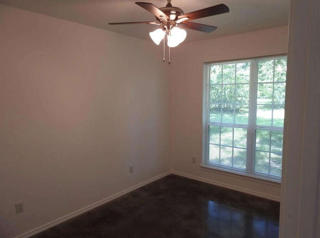 704 Seven Oaks Road Bonham, TX 75418 - Photo 4 of 11 Room featuring a multi-pane window with blinds, a ceiling fan with integrated lighting, neutral wall paint, and dark-toned flooring
