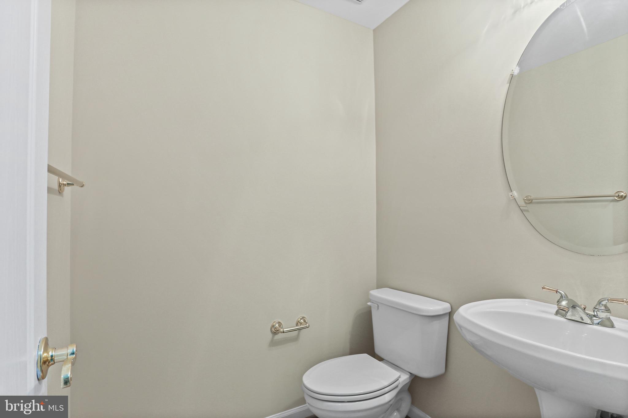10232 Rutland Round Road, Unit 24 Columbia, MD 21044 - Photo 27 of 31 a white toilet sitting next to a white sink and a mirror