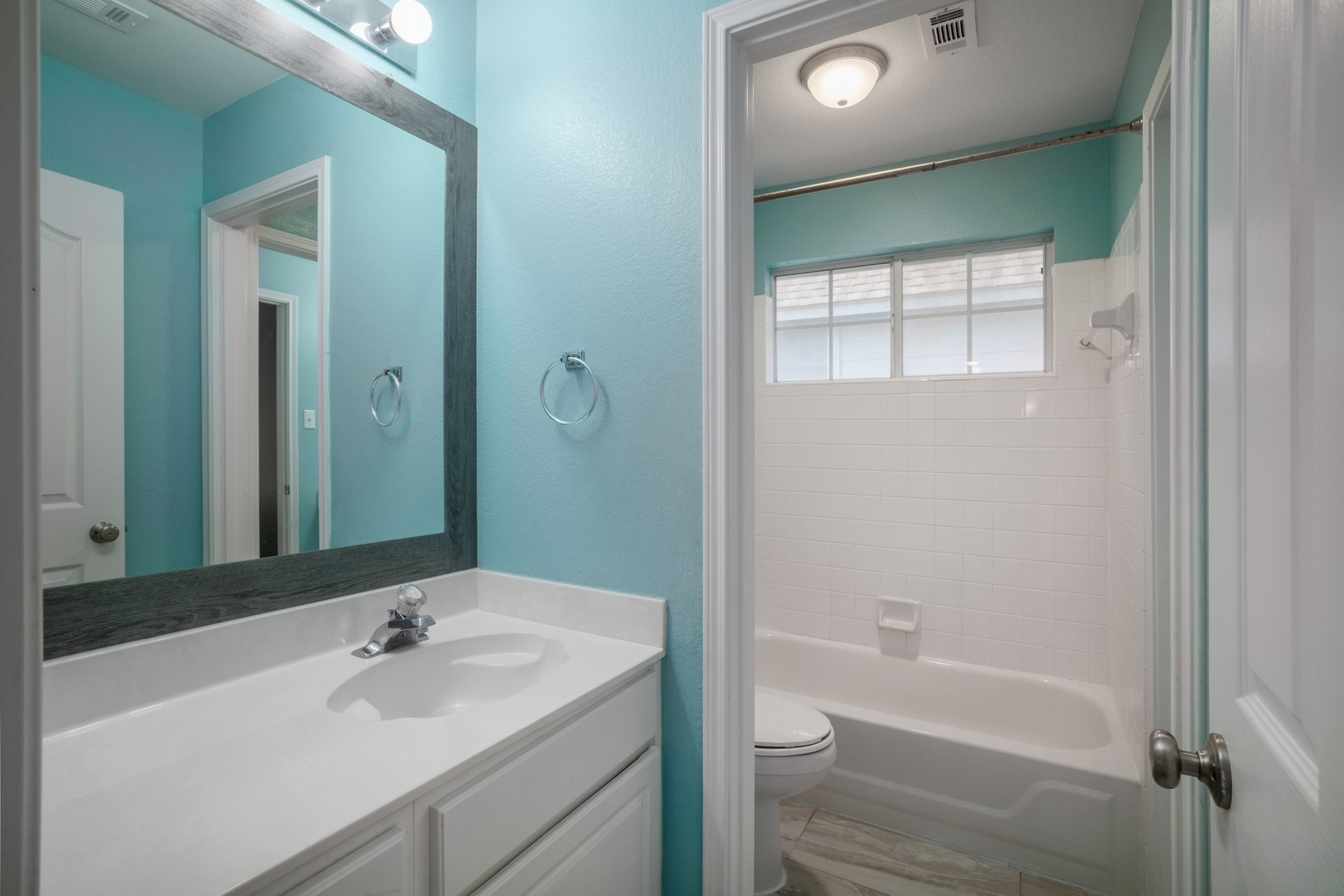 7113 Bending Oak Road Austin, TX 78749 - Photo 31 of 39 A framed vanity mirror and integrated sink countertop sit adjacent to the tiled bath area.