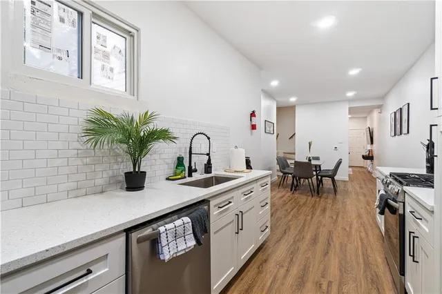a kitchen with stainless steel appliances a sink a counter space and living room view