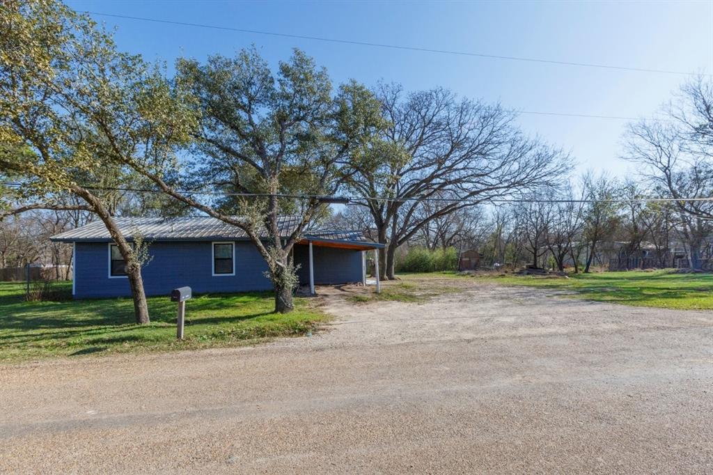 a view of a house with a yard and large trees