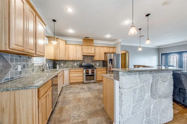 a kitchen with stainless steel appliances kitchen island granite countertop a stove a sink and a refrigerator