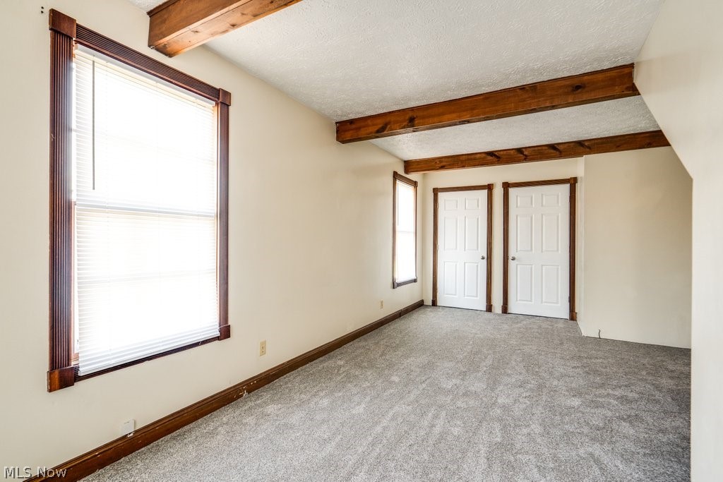 3693 Fishcreek Road Stow, OH 44224 - Photo 11 of 23 Empty room with a textured ceiling, a wealth of natural light, beam ceiling, and carpet flooring