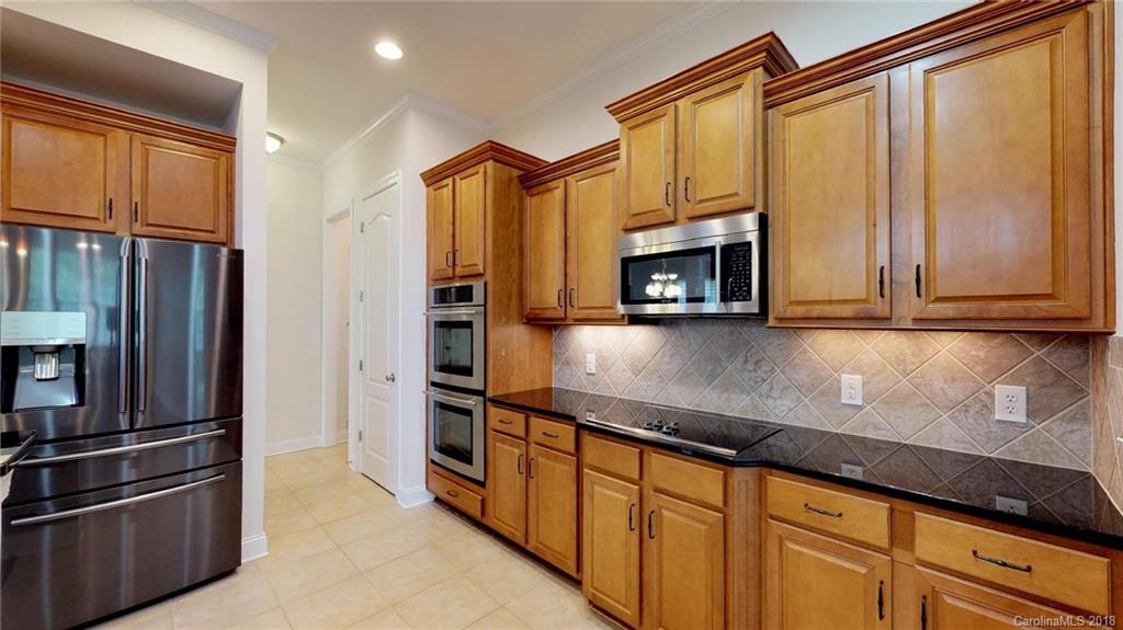 1369 Secret Path Drive Fort Mill, SC 29708 - Photo 7 of 22 a kitchen with stainless steel appliances granite countertop a refrigerator a stove and a sink with wooden floor
