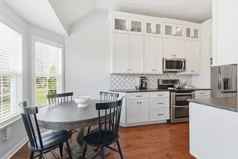 a kitchen with stainless steel appliances a stove a table and chairs