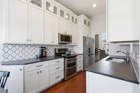 a kitchen with stainless steel appliances granite countertop a sink a stove and a refrigerator with wooden floor