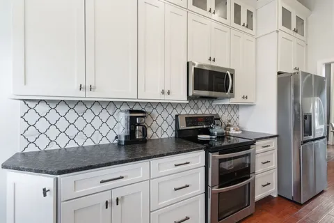 a kitchen with granite countertop white cabinets and stainless steel appliances
