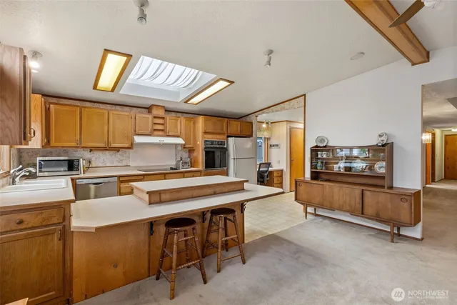 a kitchen with stainless steel appliances granite countertop a stove a sink dishwasher and a refrigerator with wooden cabinets