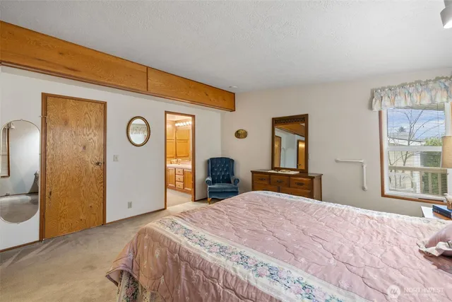 a bedroom with a bed and a large mirror next to a window