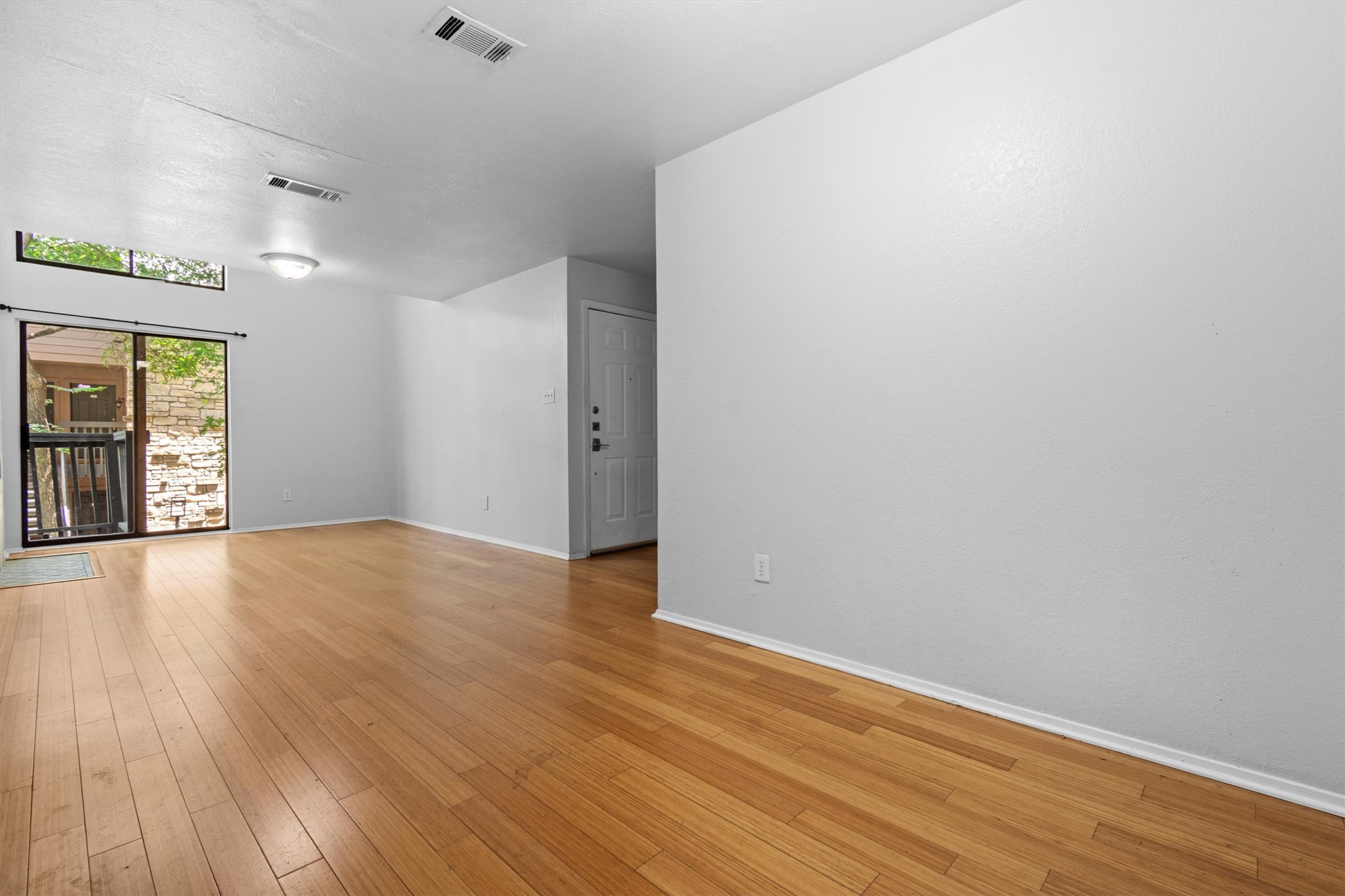 3627 Menchaca Road, Unit 204 Austin, TX 78704 - Photo 5 of 23 Natural light floods this living area, showcasing polished hardwood floors and a glass sliding door.