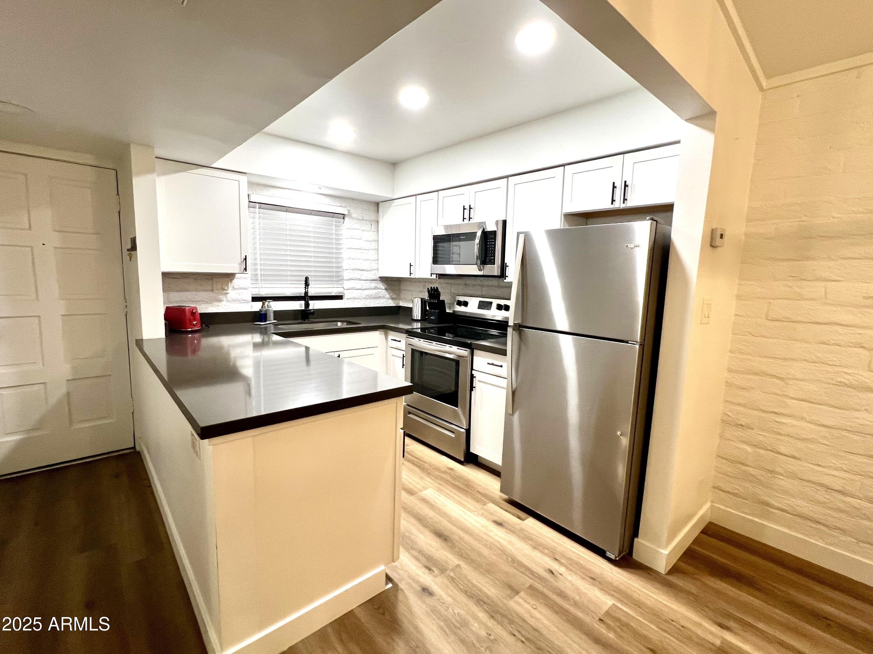 3046 North 32nd Street, Unit 333 Phoenix, AZ 85018 - Photo 4 of 16 a kitchen with granite countertop stainless steel appliances a refrigerator a stove top oven and wooden floor