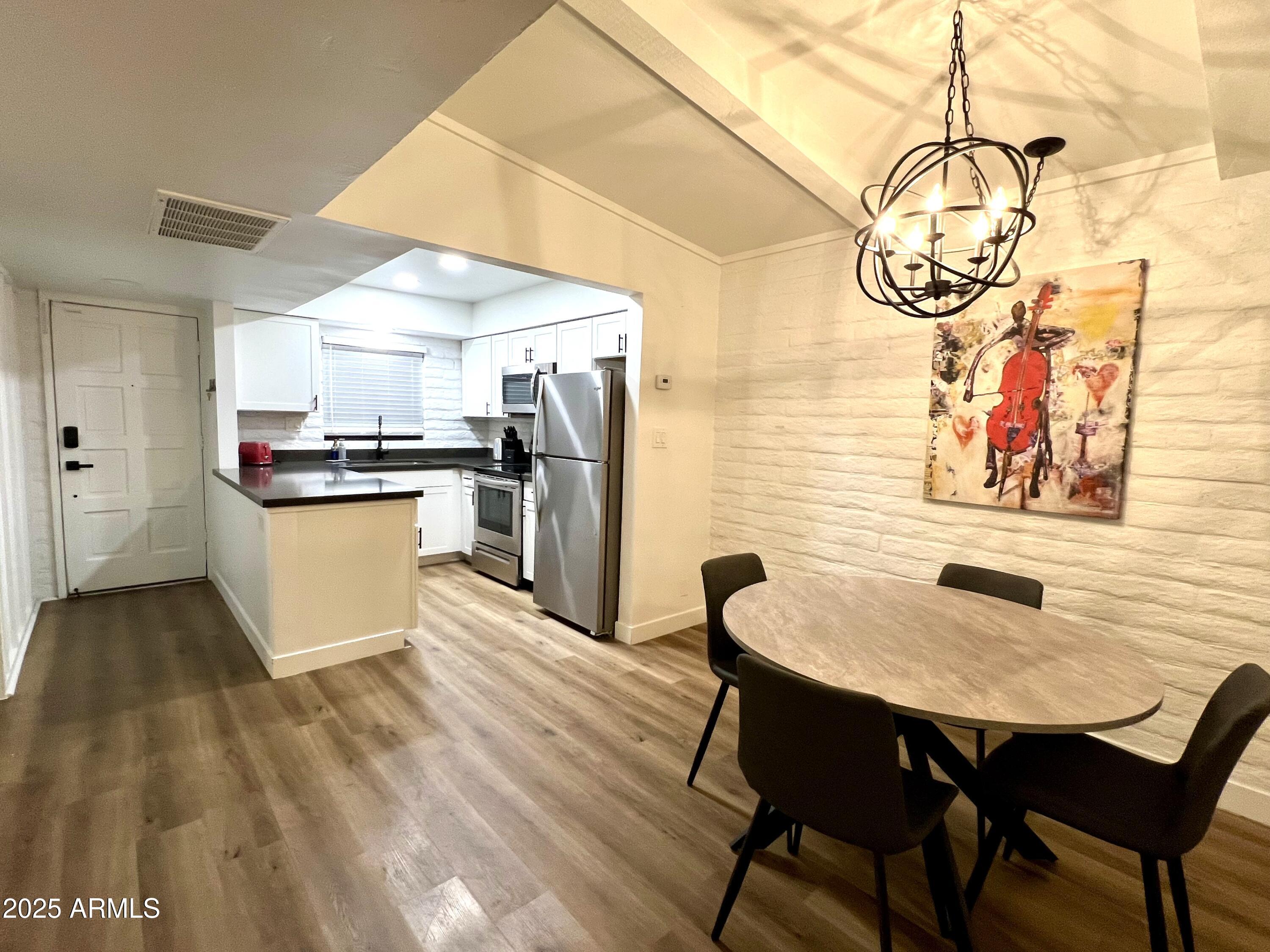 3046 North 32nd Street, Unit 333 Phoenix, AZ 85018 - Photo 5 of 16 a kitchen with stainless steel appliances granite countertop a sink a stove and chairs with wooden floor