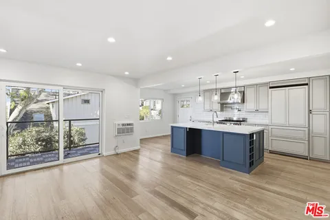 a large kitchen with a center island wooden floor and stainless steel appliances