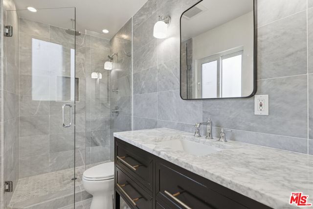 a bathroom with a granite countertop sink a toilet and shower